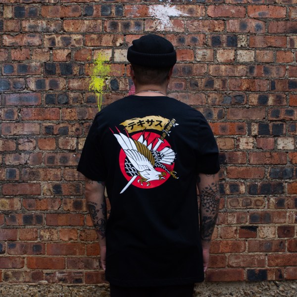A man wearing a Dallas-themed T-shirt with the word “Texas” written in Japanese and a majestic eagle and sword design by a local artist.