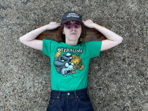 Woman lying on cement wearing a green Come to Deep Ellum t-shirt